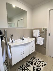 La salle de bains est pourvue d'un lavabo blanc et d'un miroir. dans l'établissement The Klein House, à Whanganui
