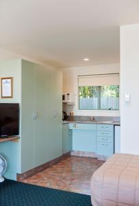 a room with a bed and a kitchen at ASURE Ashley Motor Lodge in Timaru