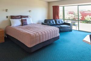 a bedroom with a large bed and a couch at ASURE Ashley Motor Lodge in Timaru