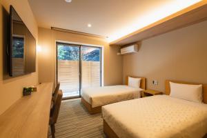 a hotel room with two beds and a window at GRAND BASE Fukuoka Tenjin in Fukuoka