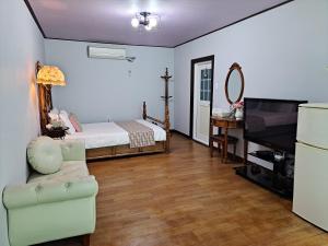 een slaapkamer met een bed, een bank en een televisie bij Charm Pension in Gapyeong
