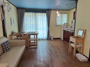een woonkamer met een bank en een tafel en een keuken bij Charm Pension in Gapyeong