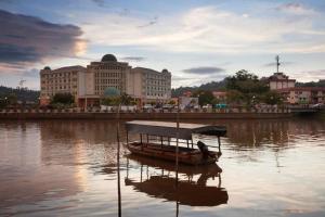 Hotel Seri Malaysia Lawas في لاواس: قارب صغير في الماء امام المدينة