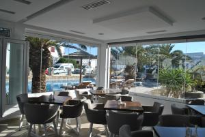 um restaurante com mesas e cadeiras e uma piscina em Petinaros Hotel em Míconos