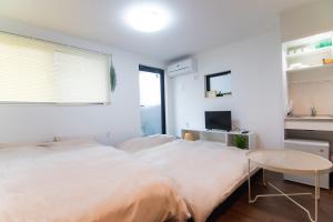 a white bedroom with a large bed and a table at Base Hanegi Apartment in Tokyo