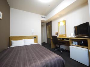 Habitación de hotel con cama, escritorio y TV. en Hotel Route-Inn Obihiro Ekimae en Obihiro
