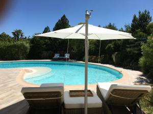 a swimming pool with an umbrella and two chairs and a table at L' Esmerand in Cotignac