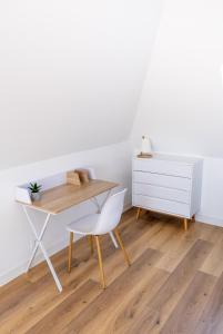 einen Schreibtisch und einen Stuhl in einem Zimmer mit einer weißen Wand in der Unterkunft Le Relais De La Ravine in Vernon
