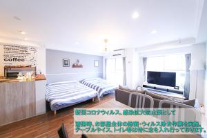 een woonkamer met een bank en een tv bij Guest House Re-worth Yabacho1 202 in Nagoya