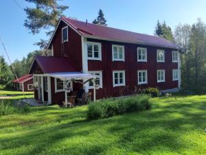 a red barn with white trim on a grass field at Soltorp Eco Lodge in Porvoo