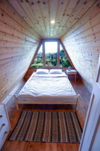 een bed in een houten kamer met een groot raam bij Kamonkő Panoráma Kuckó in Szigliget