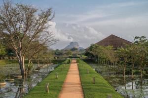 un camino en un jardín con una montaña en el fondo en Water Garden Sigiriya - 30 Chic Designed Private Villas Overlooking Sigiriya, en Sigiriya