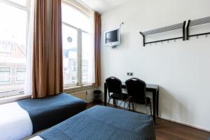 a bedroom with two beds and a desk and two chairs at Quentin Arrive Hotel in Amsterdam