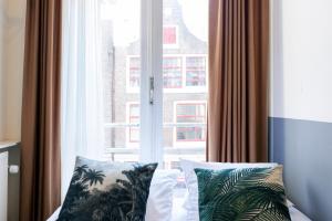 een slaapkamer met een raam met uitzicht op een gebouw bij Quentin Arrive Hotel in Amsterdam