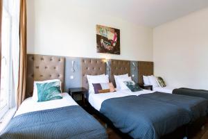 a bedroom with two beds and a headboard at Quentin Arrive Hotel in Amsterdam