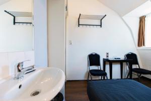 a bathroom with a sink and two chairs and a table at Quentin Arrive Hotel in Amsterdam +59 photos