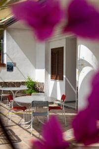 een tafel en stoelen op een patio met paarse bloemen bij La Meriggia B&B in Pisciotta