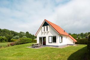 ein kleines weißes Haus mit einem Picknicktisch im Hof in der Unterkunft Vacation Home 23 in Tzummarum