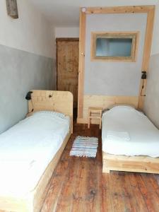 two beds in a room with wooden floors at File dans ta chambre ! in Le Monastier sur Gazeille