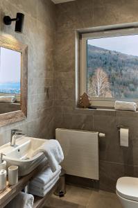 a bathroom with a sink and a toilet and a window at Między Nami Apartamenty in Szczyrk