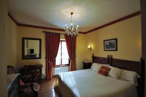 a bedroom with a large bed and a chandelier at Hotel Rural Ovio in Nueva de Llanes