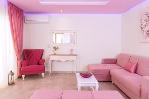 a living room with a pink couch and two red chairs at Dream View in Skala Marion