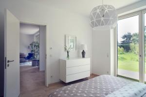 Dormitorio blanco con cómoda blanca y lámpara en Luxus Appartement zwischen Leipzig und Cospudener See en Leipzig