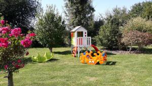 un parque infantil con una pequeña casa en el césped en Auberge aux Marais en Montmartin-en-Graignes