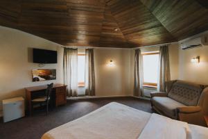 a bedroom with a bed and a couch and a desk at Geneva Park Hotel in Odesa