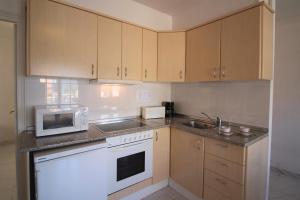 エンプリアブラバにあるBasic Comfort Apartment Club Nautic 0035のキッチン(木製キャビネット、白い電子レンジ付)