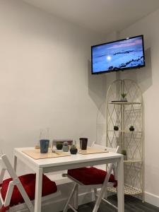 a white table and chairs with a tv on a wall at AZUR in Saint-Nazaire