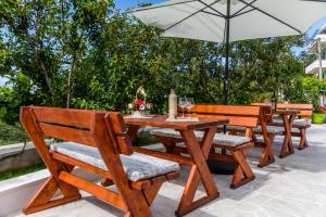 a group of wooden tables and chairs with an umbrella at Alt Braic Villa in Budva