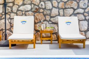 two chairs sitting in front of a stone wall at Alt Braic Villa in Budva
