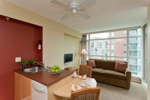a kitchen and living room with a couch and a table at Lord Stanley Suites On The Park in Vancouver