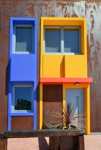 un edificio con puertas de colores diferentes y un banco de madera en CELTAINER en Maceda