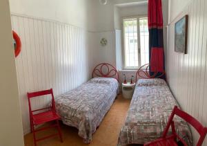 グラードにあるLa Casa Di Francaの赤い椅子と窓が備わる客室で、ベッド2台が備わります。