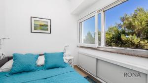 Pokój z dużym oknem i niebieskimi poduszkami w obiekcie Rona Apartment Flower 1 and Flower 2 w Novalji
