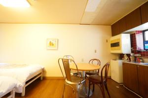 mały pokój z łóżkiem, stołem i krzesłami w obiekcie Tomato House Takayama w mieście Takayama