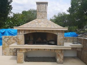 a stone oven with a stove in a yard at Apartmani Manda in Omišalj