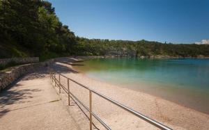 a beach with a metal railing next to the water at Apartmani Manda in Omišalj