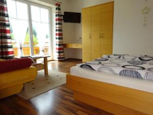 a bedroom with a bed and a couch and a window at Haus ÖtscherTeufel in Lackenhof