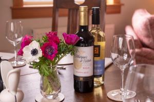 una botella de vino y flores en una mesa con copas en Blairchroisk Cottage en Pitlochry