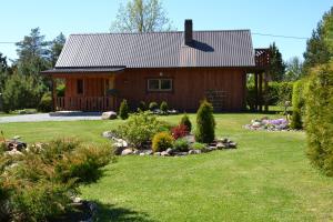 una cabaña de madera con un patio con flores en Nõmme Holiday Home, en Pamma