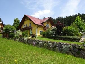 Casa amarilla con techo rojo y pared de piedra en Haus ÖtscherTeufel en Lackenhof