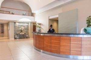 a man sitting at a reception counter in a hospital lobby at Town Lodge Roodepoort in Roodepoort