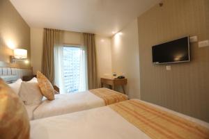 a hotel room with two beds and a flat screen tv at Hotel Cliffton in Mumbai