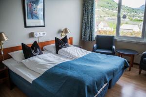 a bedroom with a bed with a blue blanket and a window at Leikanger Fjordhotel - Unike Hoteller in Leikanger +53 photos
