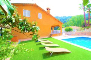una casa con una fila de tumbonas junto a una piscina en V&V LLORET - VILLA CANYELLES preciosa villa para 8PAX con piscina privada y barbacoa a solo 800m de playa Cala Canyelles, en Lloret de Mar