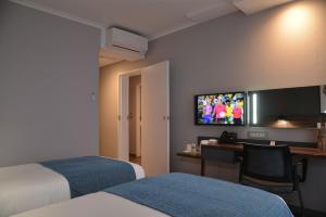 um quarto de hotel com duas camas e uma secretária e uma televisão em Town Lodge Umhlanga em Durban