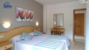 a bedroom with a white bed with blue pillows at Pension Playa Mar Cachadiñas in Balea +17 photos